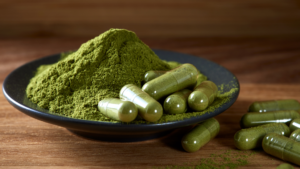 Empty capsules filled with green powder next to a mound of loose herbal powder