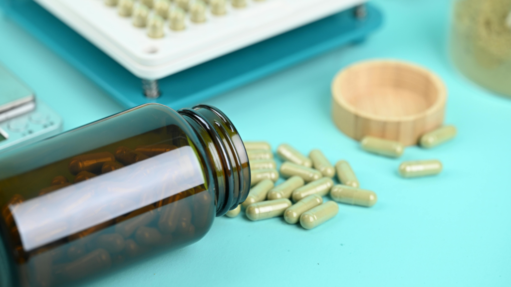 Filled herbal capsules spilled from bottle beside capsule filling tray