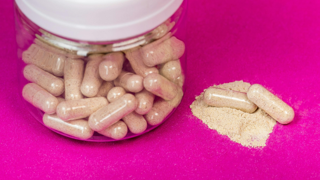 Herbal powder capsules spilling from jar next to loose herb powder