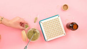Manual capsule filling machine tray loaded with capsule pins next to powder and empty shells