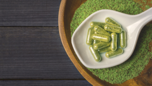 Spoonful of filled capsules resting on loose powder, illustrating how to fill capsules at home
