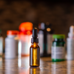 Amber tincture dropper bottle among supplement containers_ representing a liquid capsule filling machine setup.