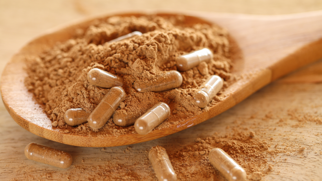 Capsules and loose powder on a wooden spoon_ showing the cost to fill your own capsules at home