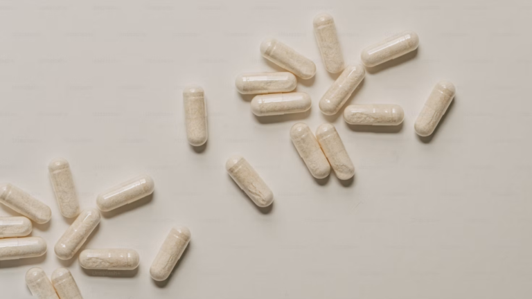 Loose off-white vegan capsules scattered on a plain white background.