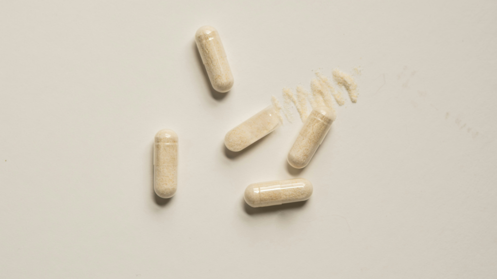 Powder-filled capsules scattered on a table with loose powder spilling from one capsule