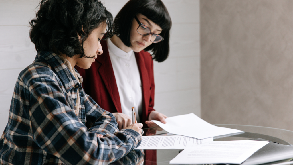 Two people reviewing business registration paperwork at a desk.