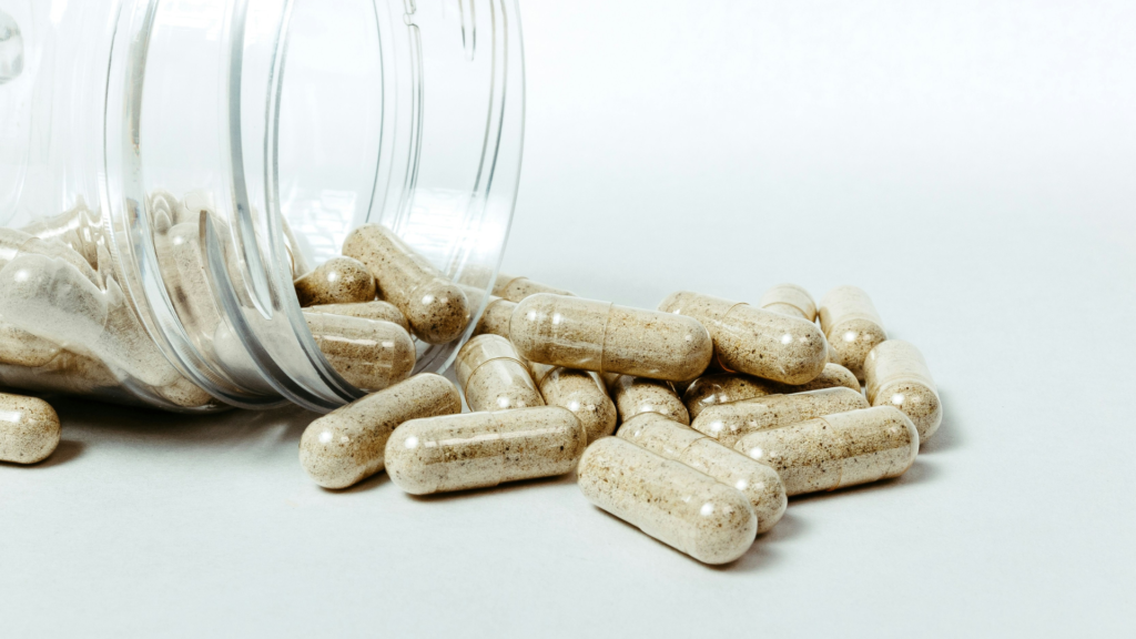 Vegan capsules spilling out of a clear glass jar