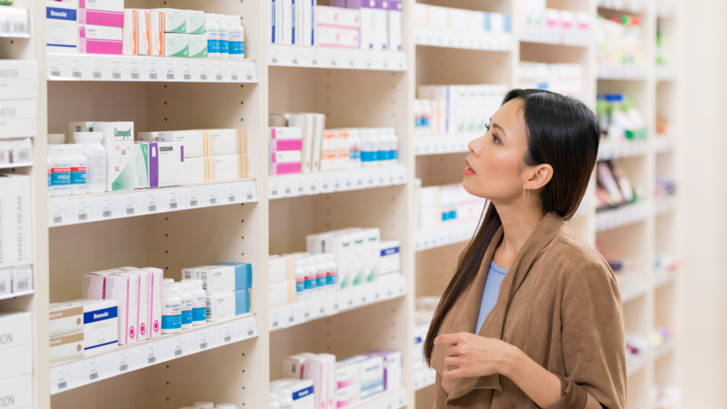 Woman browsing pharmacy shelves looking for empty capsules.